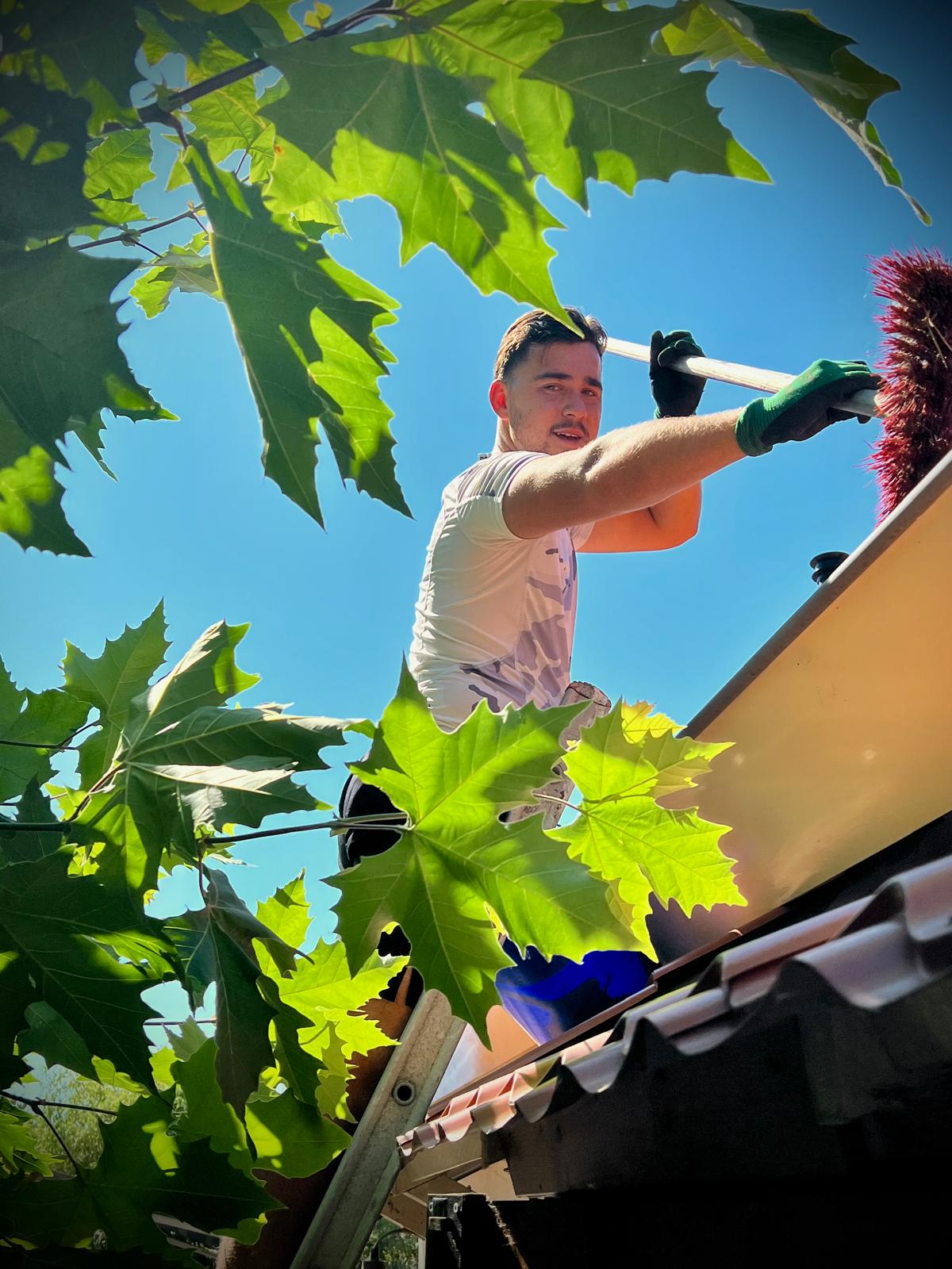 Specialist veegt dakgoot schoon